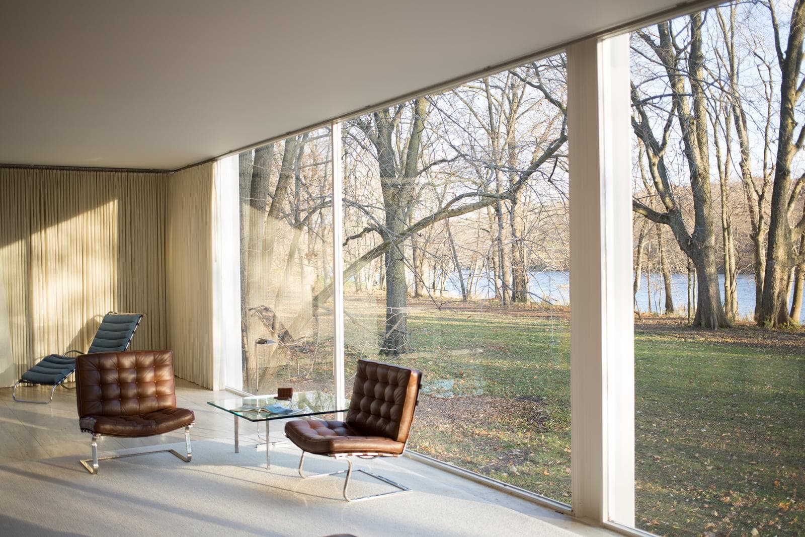 Planta livre da Farnsworth House: Ambientes integrados com painéis de madeira centralizados e ausência de paredes cegas.